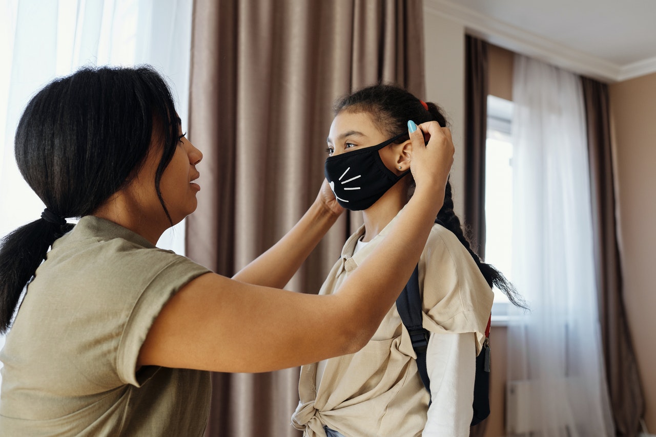 A mother putting a mask on her child representing parental disputes over covid issues